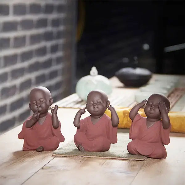 Statues Moine de la Sagesse Céramique Robe Rouge les trois alignées sur une table en bois kaosix